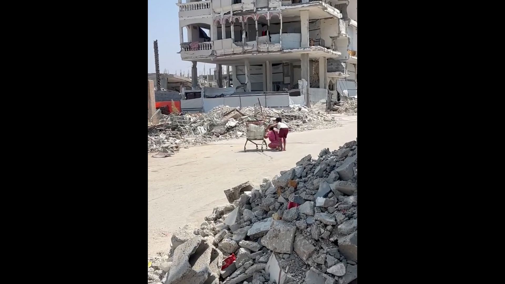 Gaza children seek shelter from Israeli drone fire behind shopping cart