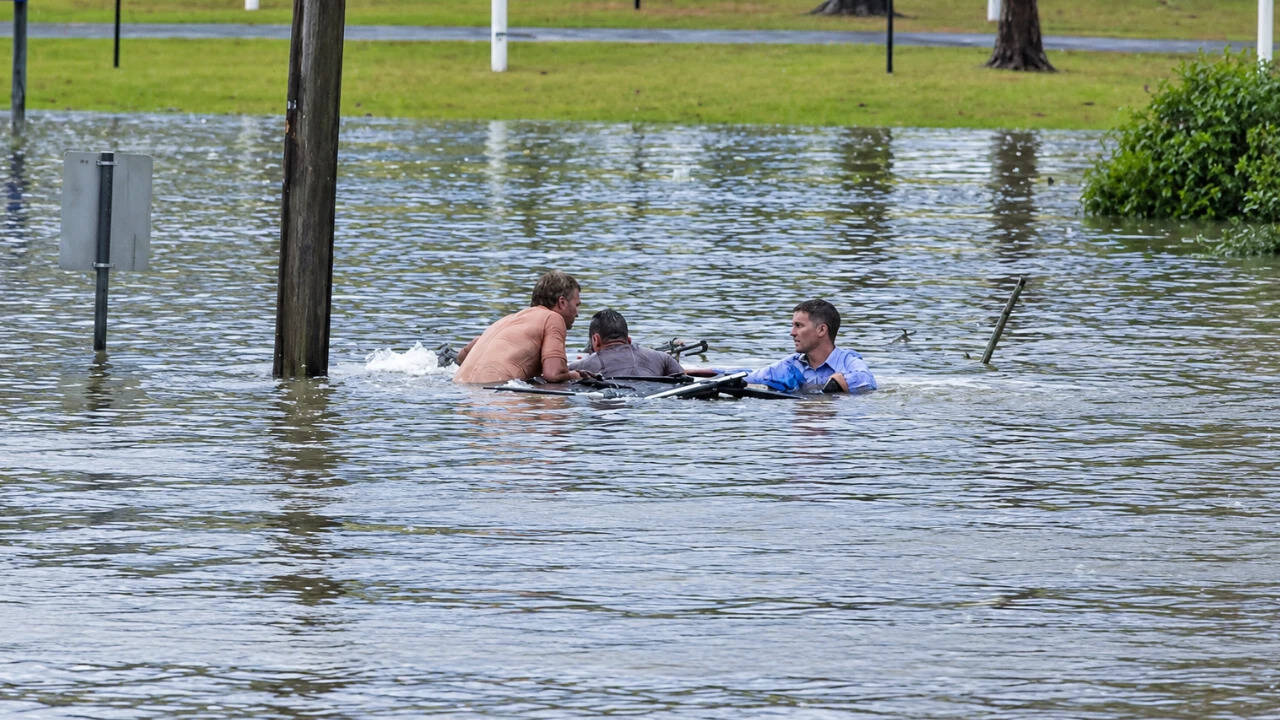 Journalist and bystander rescue driver from submerged vehicle in floodwaters